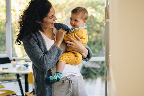 Junge Frau verbringt Zeit mit ihrem bezaubernden Kind zu Hause. Frau trägt ihr Baby und lächelt. - JLPSF08261