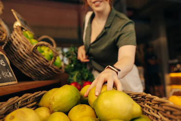 Zufriedene Kundin, die in der Frischwarenabteilung eines Lebensmittelgeschäfts einige Bio-Früchte auswählt. Unbekannte Frau beim Einkaufen in einem trendigen Supermarkt. - JLPSF08305
