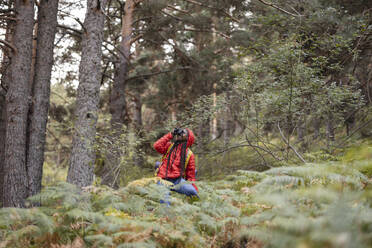 Junge Frau fotografiert durch Kamera im Wald - JCCMF07439