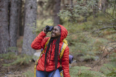 Glückliche Frau beim Fotografieren durch die Kamera im Wald - JCCMF07440