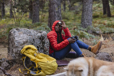Frau mit Taschenlampe sitzt mit Kamera im Wald - JCCMF07456