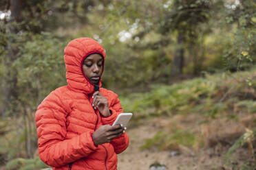 Young woman using smart phone in forest - JCCMF07461