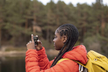 Junge Frau mit geflochtenem Haar beim Fotografieren mit dem Smartphone - JCCMF07468