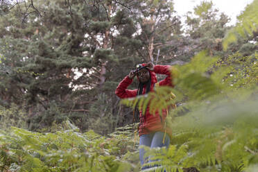 Frau mit Taschenlampe auf der Stirn steht inmitten von Pflanzen - JCCMF07476