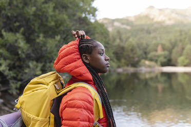 Young woman with backpack by lake at vacation - JCCMF07481