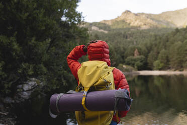 Young woman standing with backpack in front of lake - JCCMF07483