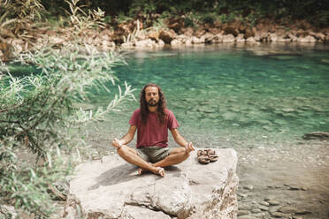 Young man meditating on rock in front of Tara river - PCLF00173