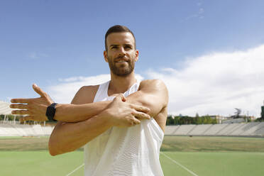 Man doing stretching exercise on sports field - IFRF01782