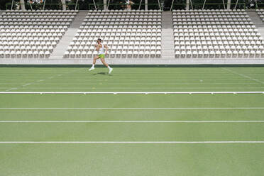 Ein Sportler übt an einem sonnigen Tag das Laufen auf einer Sportbahn - IFRF01793