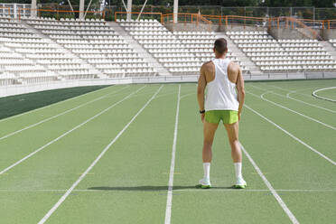 Athlete standing on running track on sunny day - IFRF01797