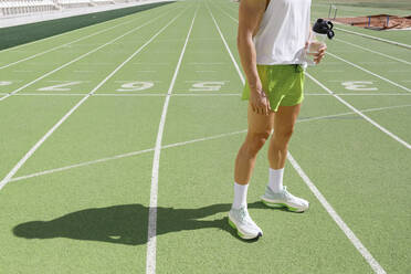 Athlete holding water bottle at sports track - IFRF01808