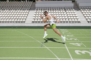 Man running on sports track on sunny day - IFRF01821