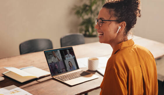 Geschäftsfrau lacht während eines Videogesprächs mit ihrem Team. Frau, die von zu Hause aus arbeitet und eine Videokonferenz mit Kollegen abhält. - JLPSF08383