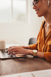 Eine Frau schreibt einen Blog auf einem Laptop. Eine Bloggerin arbeitet zu Hause an einem Laptop. - JLPSF08385