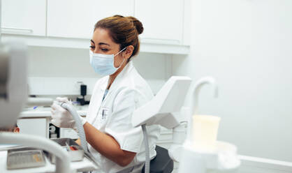 Zahnärztin bei einer Zahnbehandlung an den Zähnen eines Patienten mit Werkzeugen. Zahnärztin mit Gesichtsmaske bei der Arbeit in ihrer Klinik. - JLPSF08426