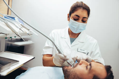 Eine Zahnärztin überprüft die Zähne eines männlichen Patienten. Ein Zahnarzt behandelt einen männlichen Patienten in einer Zahnklinik. - JLPSF08434