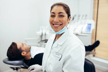 Lächelnde Zahnärztin in einer Zahnklinik, Zahnärztin in einer Klinik mit einem Patienten auf dem Zahnarztstuhl. - JLPSF08439