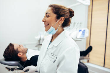 Happy female dentist in dental clinic. Woman dental doctor with a male patient in dentist's chair. - JLPSF08440