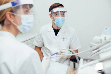 Dental doctors wearing face shields and masks during dental treatment. Dentists treating a patient with dental equipment. - JLPSF08452