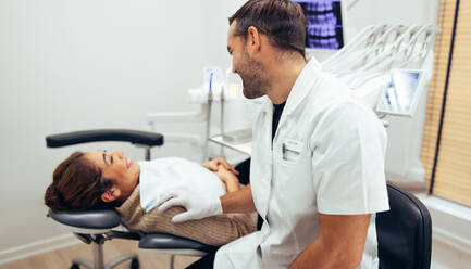 Dentist talking with a female patient sitting in chair before the treatment. Female patient and dentist smiling in dentistry. - JLPSF08458