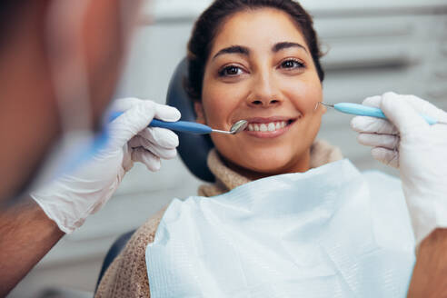 Lächelnde Frau, die ihre Zähne vom Zahnarzt überprüfen lässt. Frau bei zahnärztlicher Untersuchung in der Klinik. - JLPSF08467