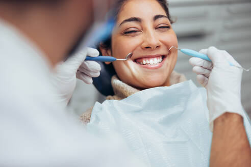 Over the shoulder view of a dentist examining a patients teeth in dental clinic. Female having her teeth examined by a dentist. - JLPSF08469