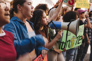 Eine Gruppe multikultureller Jugendlicher, die mit Transparenten und einem Megaphon für Klimagerechtigkeit demonstrieren, protestiert in der Stadt gegen die globale Erwärmung und den Klimawandel. - JLPSF08486