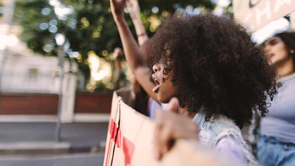 Demonstration in der Stadt. Eine Gruppe aktiver junger Menschen hebt die Fäuste und skandiert Slogans während einer Anti-Kriegs-Demonstration. Junge Menschen marschieren mit Plakaten durch die Straßen. - JLPSF08542