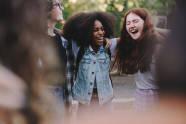 Glückliche Schulkinder im Teenageralter, die sich gegenseitig umarmen, während sie in einem Kreis stehen. Gruppe multikultureller junger Menschen in einem Huddle. - JLPSF08561