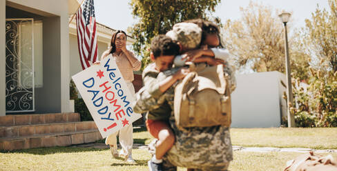 Patriotischer Soldat, der von seiner Familie zu Hause empfangen wird. Amerikanischer Soldat, der seine Kinder nach der Rückkehr aus der Armee umarmt. Militärischer Mann, der mit seiner Frau und seinen Kindern wieder zusammenkommt. - JLPSF08722