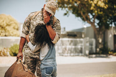 Emotionale militärische Wiedervereinigung zwischen Vater und Tochter. Militärischer Vater weint vor Freude, während er seine Tochter bei seiner Heimkehr umarmt. Soldat, der von seinem Kind nach einem Einsatz herzlich begrüßt wird. - JLPSF08724