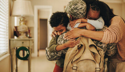 Emotionale militärische Heimkehr. Patriotischer Soldat, der nach seinem Dienst in der Armee wieder mit seiner Frau und seinen Kindern zusammenkommt. Soldat, der seine Familie nach der Heimkehr von einem Einsatz umarmt. - JLPSF08727