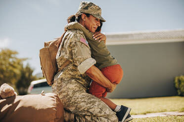 Emotionale Militärmutter, die ihren Sohn nach der Rückkehr aus der Armee umarmt. Mutige Soldatin, die nach einem Militäreinsatz wieder mit ihrem kleinen Kind zusammenkommt. - JLPSF08754