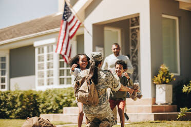 Eine Soldatin umarmt ihre Kinder, nachdem sie von der Armee nach Hause gekommen ist. Ein amerikanischer Soldat wird von seinem Mann und seinen Kindern herzlich empfangen. Eine Soldatin trifft sich wieder mit ihrer Familie. - JLPSF08792