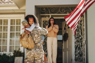 Ein Soldat umarmt seine Tochter, nachdem er nach Hause gekommen ist. Ein amerikanischer Soldat überrascht seine Frau und seine Tochter mit seiner Rückkehr. Ein Soldat, der nach einem Einsatz wieder mit seiner Familie zusammenkommt. - JLPSF08803