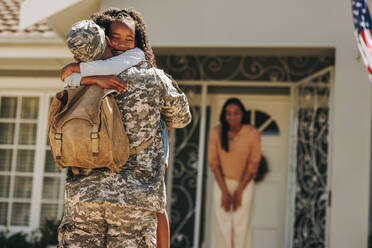 Ein Soldat umarmt seine Tochter, nachdem er nach Hause gekommen ist. Ein amerikanischer Soldat überrascht seine Frau und seine Tochter mit seiner Rückkehr. Ein Soldat, der nach einem Einsatz wieder mit seiner Familie zusammenkommt. - JLPSF08804