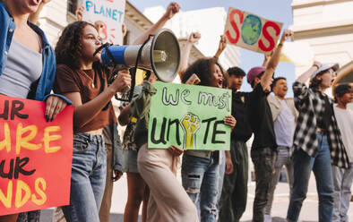 Junge Demonstranten, die für Klimagerechtigkeit und ökologische Nachhaltigkeit kämpfen. Eine Gruppe multikultureller Aktivisten protestiert mit Transparenten und einem Megaphon gegen den Klimawandel. - JLPSF08822