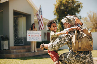 Militärischer Vater, der seine Familie zu Hause wiedersieht. Amerikanischer Soldat, der seine Kinder umarmt, nachdem er von der Armee nach Hause gekommen ist. Soldat, der von seiner Familie herzlich empfangen wird. - JLPSF09047