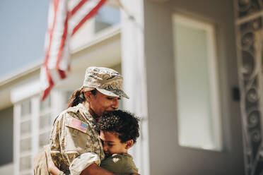 Mutter und Sohn treffen sich nach einem Militäreinsatz wieder. Emotionale Mutter umarmt ihren Sohn, nachdem sie von der Armee nach Hause gekommen ist. Patriotische Soldatin wird von ihrem kleinen Kind herzlich begrüßt. - JLPSF09086