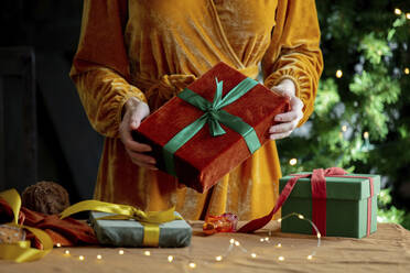 Woman standing with Christmas gifts at home - VSNF00001