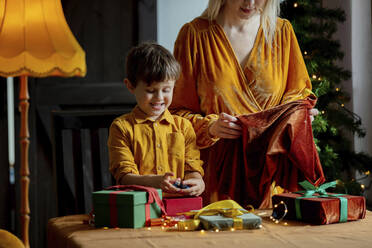 Cute boy helping mother in wrapping gifts at home - VSNF00005