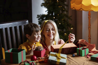 Glückliche Mutter und Sohn verpacken Geschenke zu Hause - VSNF00013