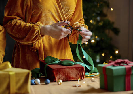 Frau schneidet Band über Weihnachtsgeschenk zu Hause - VSNF00019