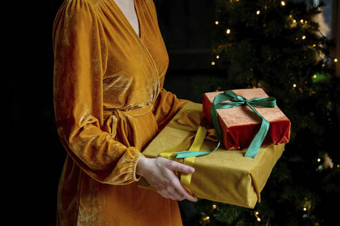 Frau mit gelbem Kleid hält Weihnachtsgeschenke zu Hause - VSNF00021