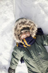 Lächelnder Junge auf Schnee liegend - ONAF00170
