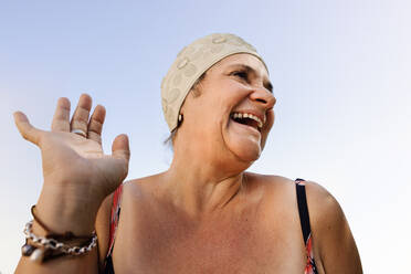 Cheerful elderly woman laughing happily in swimwear. Carefree mature woman enjoying her summer vacation at a tropical spa resort. Blissful elderly woman enjoying herself after retirement. - JLPSF09131