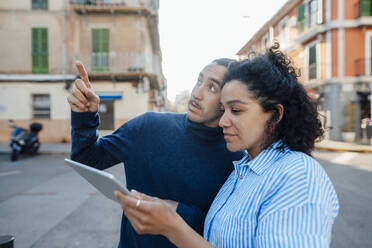 Young freelancer talking to colleague using tablet PC on road - JOSEF14503