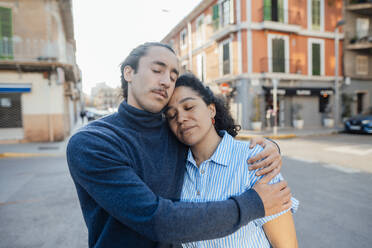 Couple embracing with eyes closed on street - JOSEF14507