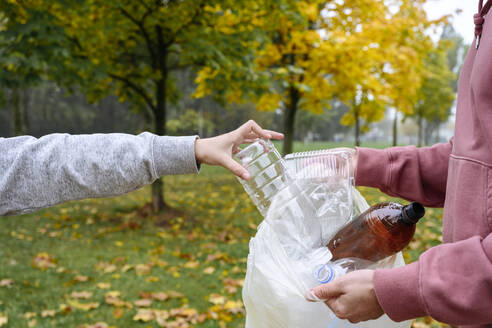 Ein Mann hält eine Plastiktüte in der Hand und ein Junge steckt eine Flasche hinein - EYAF02197