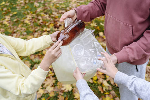 Hands of man and children collecting plastic garbage - EYAF02198